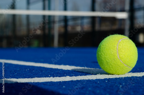Ground level image of a ball on a blue paddle tennis court lines © Vic