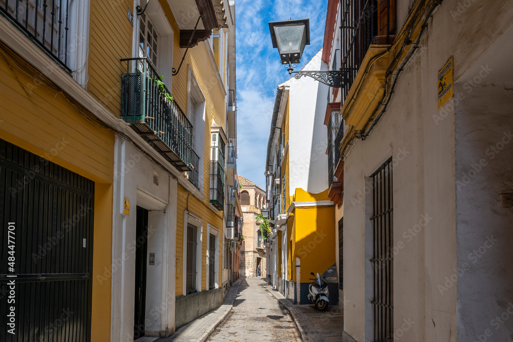 One of the typical narrow streets of shops and cafes in the Andalusian city of Seville, Spain.