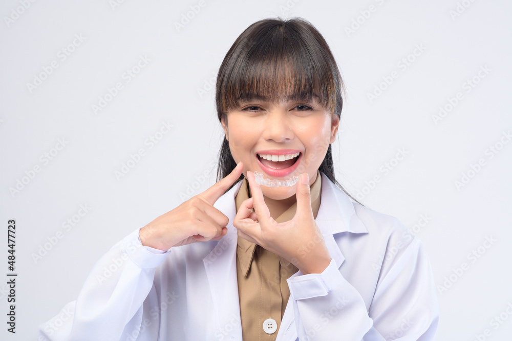 Young female dentist holding invisalign braces over white background studio, dental healthcare and Orthodontic concept. Young female dentist holding invisalign braces over white background studio, dental healthcare and Orthodontic concept.