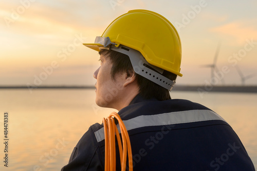 A male engineer wearing a protective helmet at sunset.. © tonefotografia
