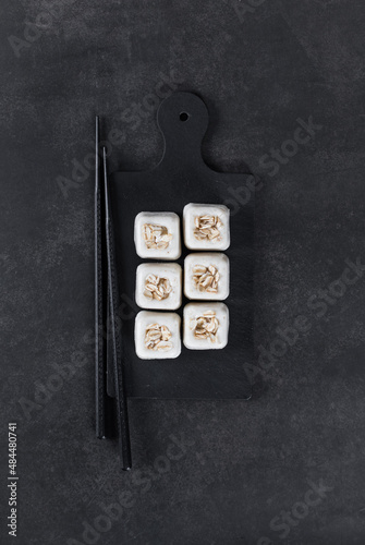 MIni oatmeal cream dessert in the shape of a square savarin on a serving board on a dark gray background. Top view