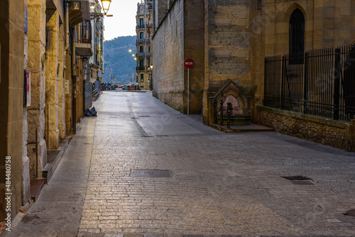 Calle 31 de Agosto, old part, old neighborhood, old city of San Sebastián Donostia, a cold winter morning, at dawn, you can see the empty street, the streetlights on, the shiny ground and the awakenin