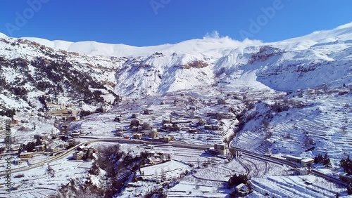 Village and mountains covered by snow. Winter aerial view. Sunny weather
