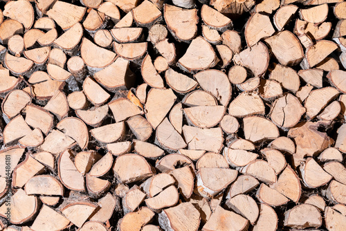 Chopped wooden logs stacked in the woodpile. Background