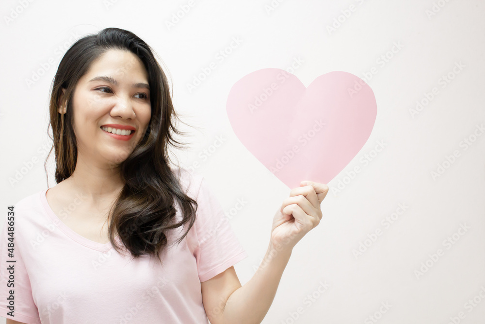 Asian beautiful woman are holding Pink heart shape paper beside her head with smile and happiness. Valentine day and Love. Asian beautiful woman are holding Pink heart shape paper beside her head with smile and happiness. Valentine day and Love.