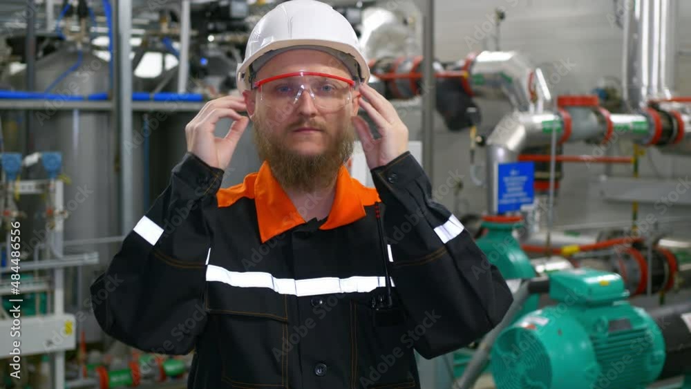 A bearded engineer in a white helmet puts on goggles in the building of an industrial production workshop for pumping oil and gas condensate. Petrochemical industry A bearded engineer in a white helmet puts on goggles in the building of an industrial production workshop for pumping oil and gas condensate. Petrochemical industry