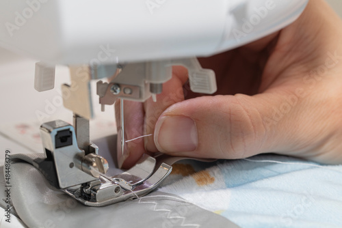 Close up of hand threading the needle on a sewing machine