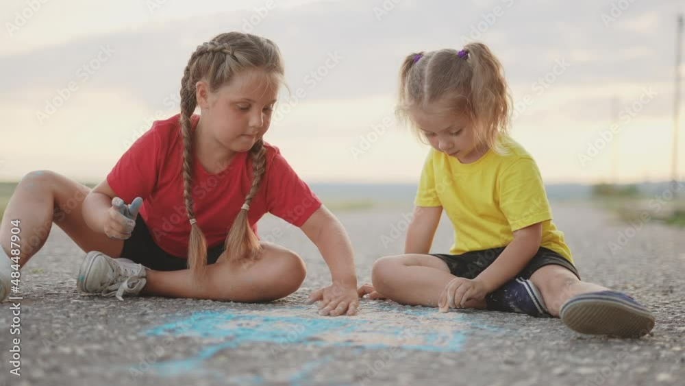 children draws a picture house with chalk on the road. happy family kid dream concept. children play with crayon art. happy childhood concept. kid drawing the house. happy family two sisters playing