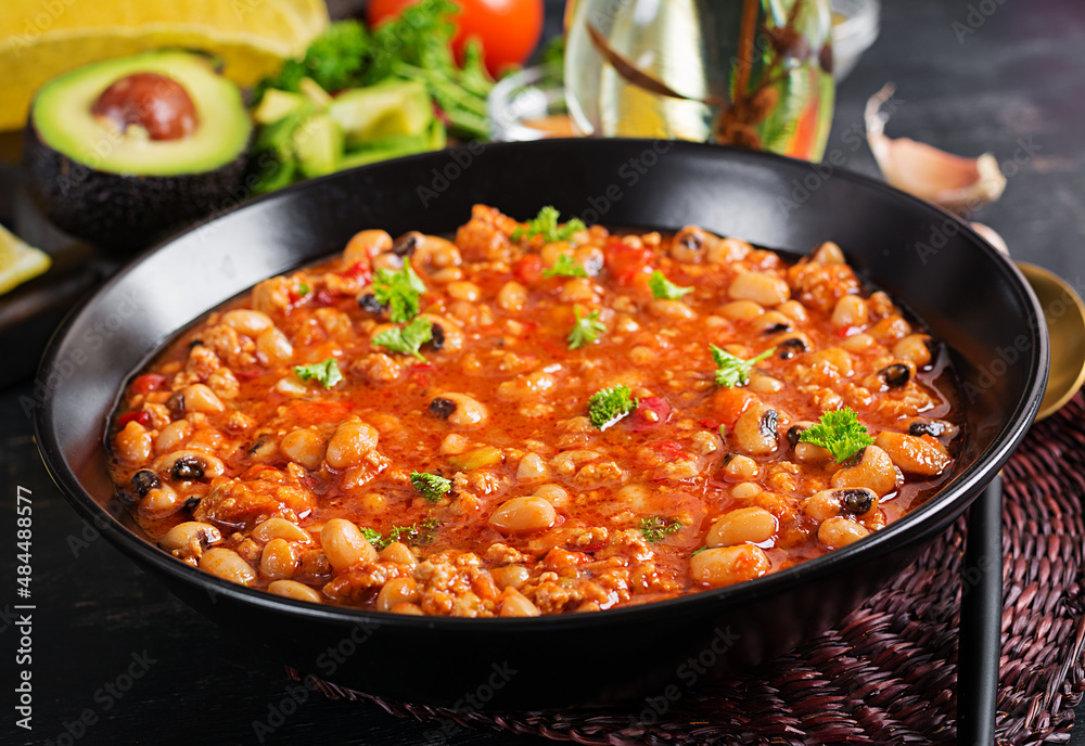Chili con carne in bowl on dark background. Mexican cuisine. Chili con carne in bowl on dark background. Mexican cuisine.