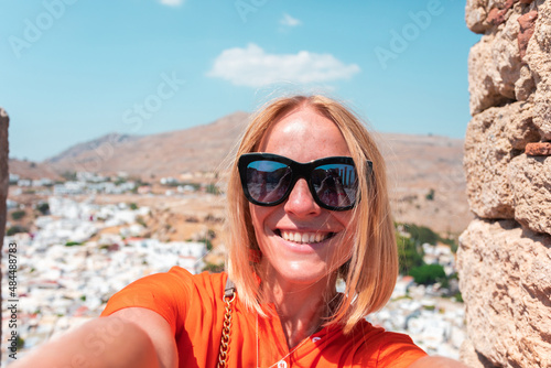 A blonde woman looks at the panorama of Lindos on the island of Rhodes, Greece © LALSSTOCK