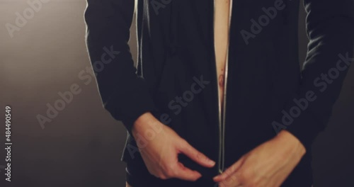 Unknown fit woman unzipping her top in the locker room after a workout at the gym.