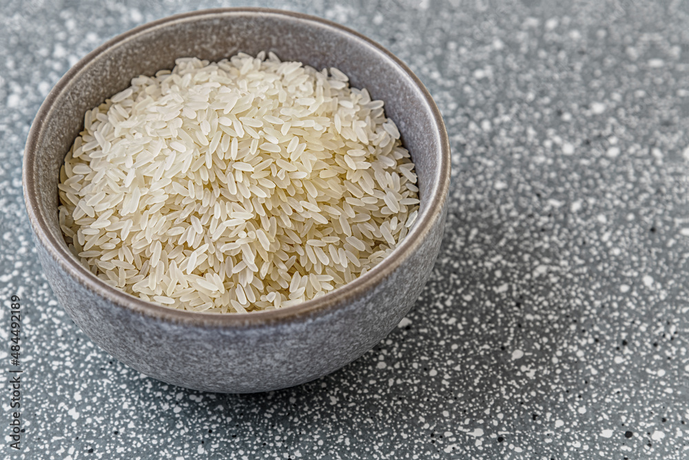 raw dry rice in a ceramic bowl on a grey plastic surface raw dry rice in a ceramic bowl on a grey plastic surface