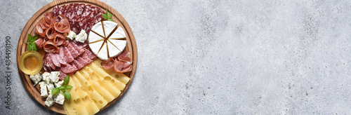 Wooden plate with delicacies. Brie cheese, blue cheese, salami, prosciutto on a wooden board.