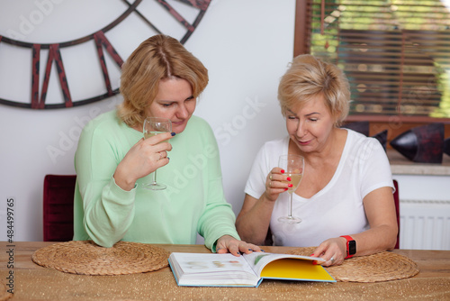 Portrait of two blond women celebrating books publication by woman writer, Drinking alcohol .Reading and discussing photo