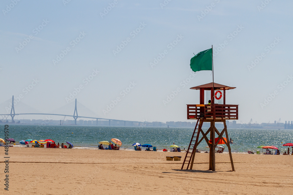 lifeguard in the surveillance beach tower with bathers bathing and sunbathing on the shore lifeguard in the surveillance beach tower with bathers bathing and sunbathing on the shore