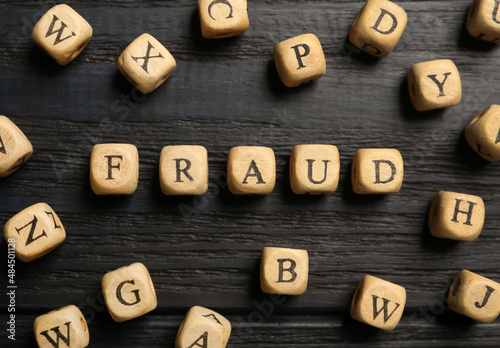 Word Fraud of cubes with letters on black wooden background, flat lay