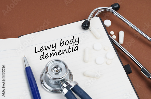 On a brown surface lie pills, a pen, a stethoscope and a notebook with the inscription - Lewy body dementia