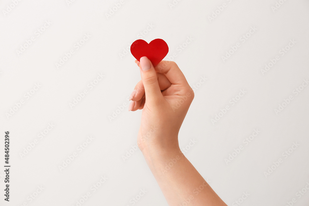 Female hand with red paper heart on color background. Donation concept Female hand with red paper heart on color background. Donation concept