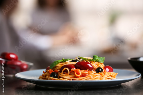 Plate of tasty Pasta Puttanesca on table in restaurant