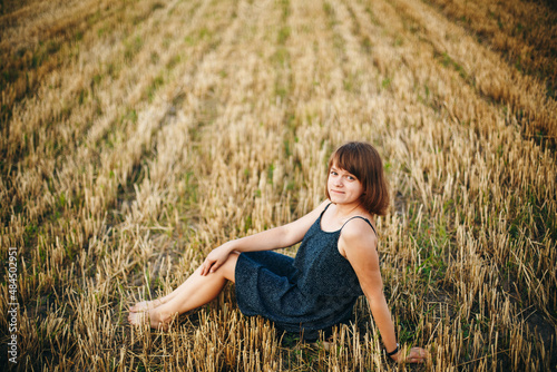 Fototapeta Naklejka Na Ścianę i Meble -  A beautiful girl and a field on which they threshed grain. Woman after harvest. Girl and yellow field

