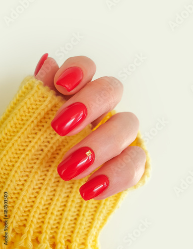 beautiful red manicure female hand  yellow sweater