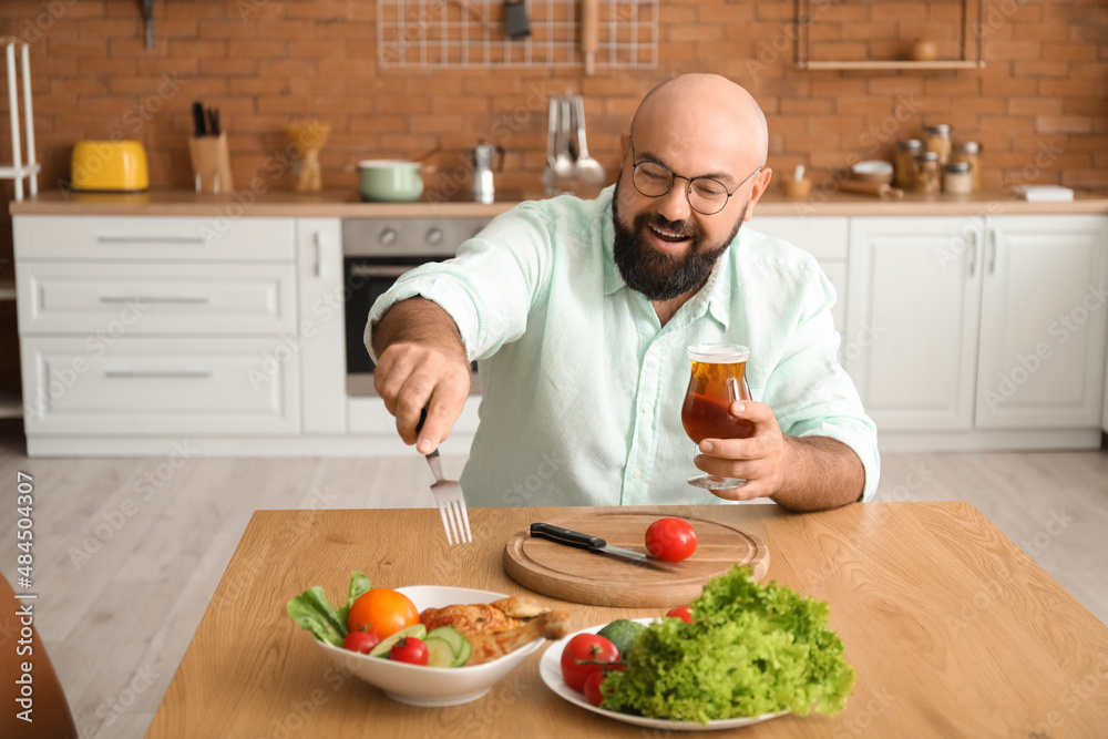 Bald man drinking beer and having lunch in kitchen Bald man drinking beer and having lunch in kitchen