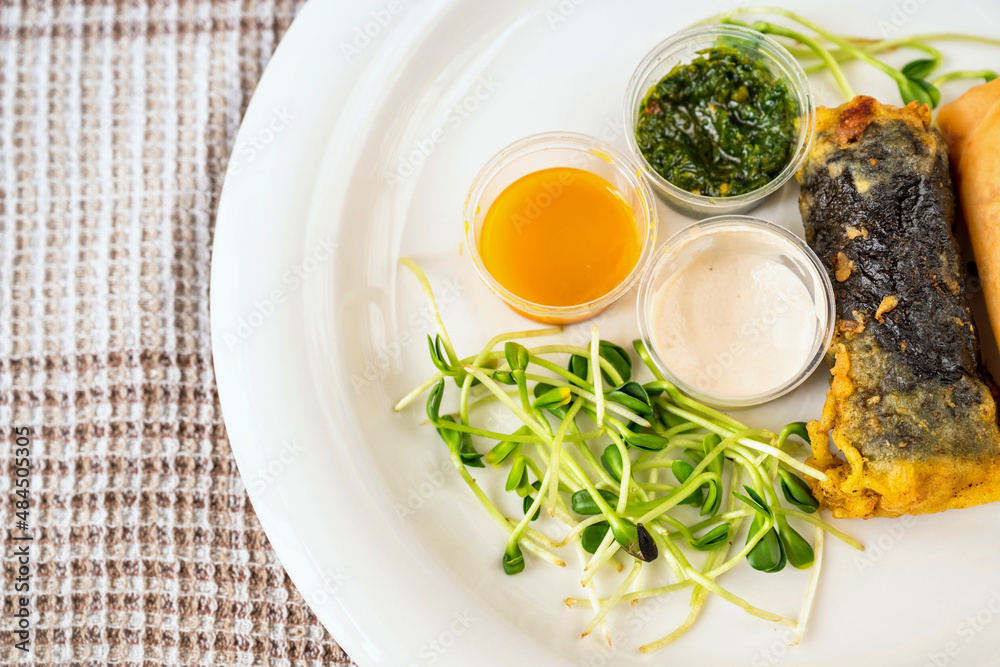 Plate with sprouted vegetable, 3 bowl with sauce, vietnamese roll with seaweed. Plate with sprouted vegetable, 3 bowl with sauce, vietnamese roll with seaweed.