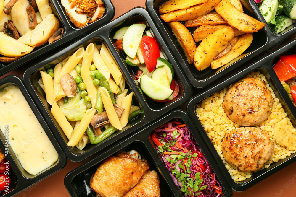 Lunch boxes with delicious meals on color background, closeup Lunch boxes with delicious meals on color background, closeup