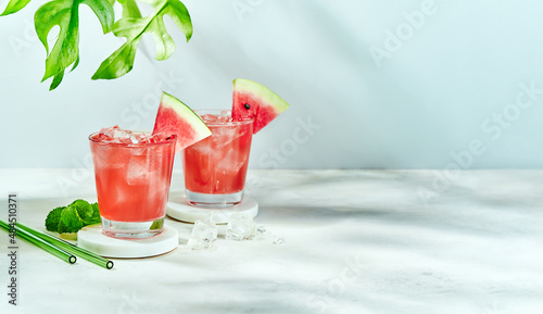 Fresh drink with watermelon and mint, cold summer lemonade, healthy mocktail. Sunny day shadows on blue sky background with copy space. Layout for wide banner.