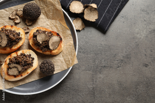 Delicious bruschettas with truffle sauce on grey table, flat lay. Space for text