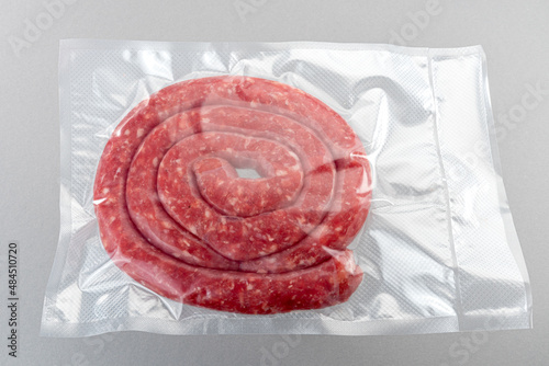 Italian sausage (salsiccia) in vacuum packed sealed for sous vide cooking isolated on grey background in top view photo