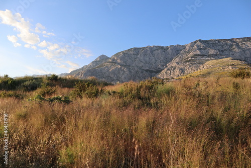 Mountain landscape rocky slopes of mountains against the blue sky and burnt grass on a sunny summer evening, Croatia, Dalmatia