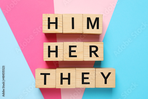 Gender pronouns Him, Her and They made of wooden cubes on color background, flat lay photo