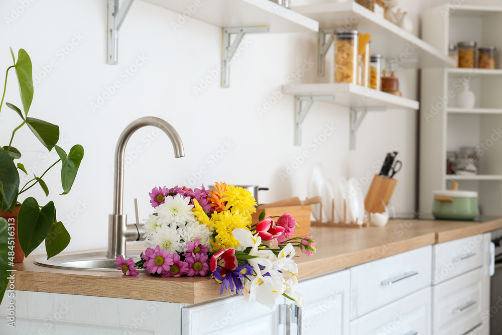 Fototapeta premium Modern light kitchen with bouquet of flowers in sink