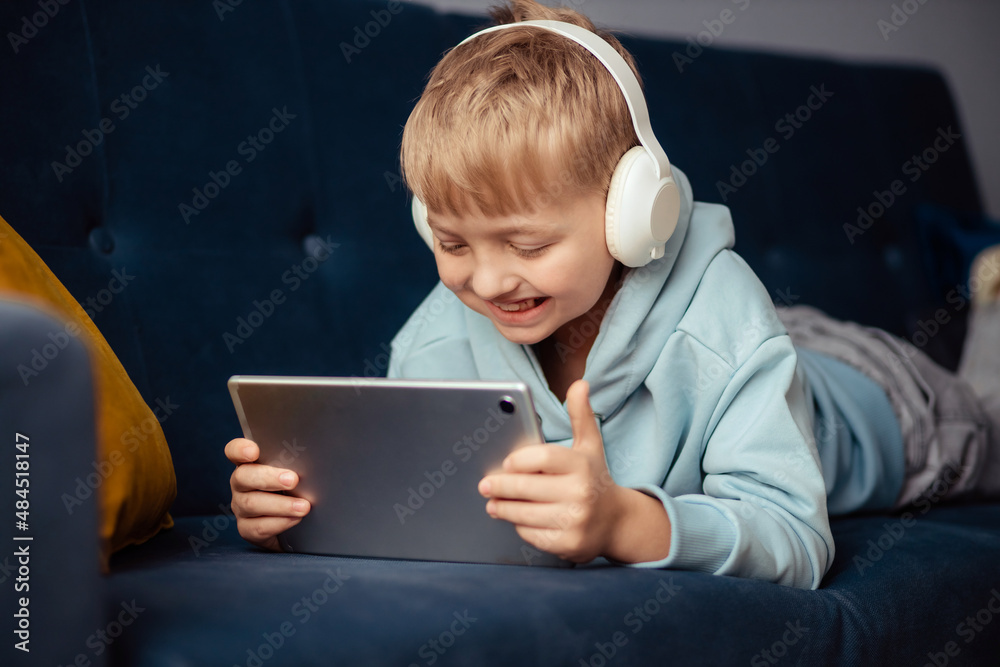 The boy at home communicates with friends on the Internet. Distance learning for children. Education, online learning, homeschooling, schoolchildren lifestyle concept The boy at home communicates with friends on the Internet. Distance learning for children. Education, online learning, homeschooling, schoolchildren lifestyle concept