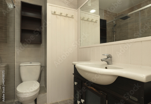 Bathroom with dark wood vanity  semicircular single sink  and white wood framed mirror