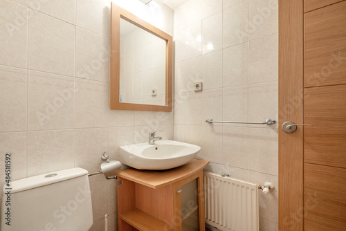 Modern bathroom with light wood cabinet and square mirror with wood frame and white china sink