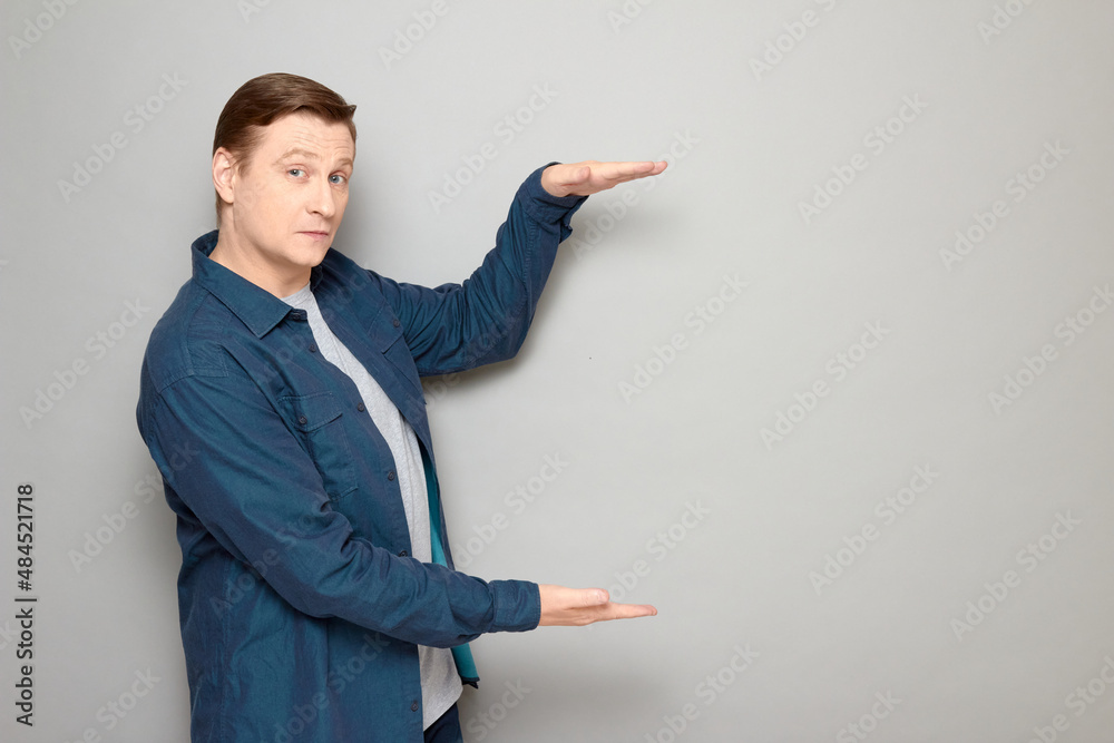 Portrait of happy mature man showing size of something with hands