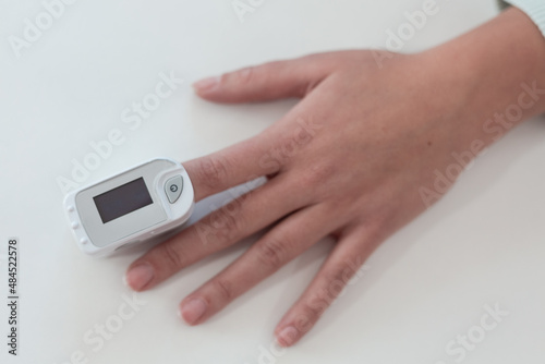 Pulse oximeter on a woman's finger. blood oxygen saturation. The patient measures the saturation of the blood with an electronic pulse oximeter on the finger