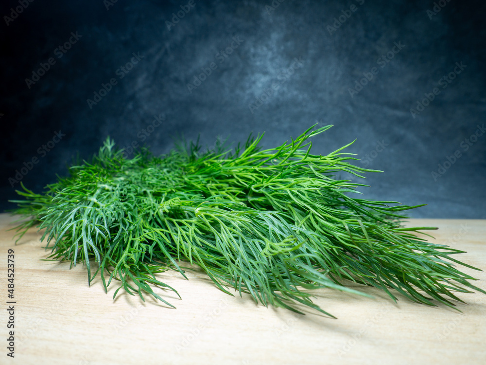 Fototapeta premium A bunch of dill on a cutting board. Useful product. Greens on the kitchen table. Vegetarian lunch ingredient.
