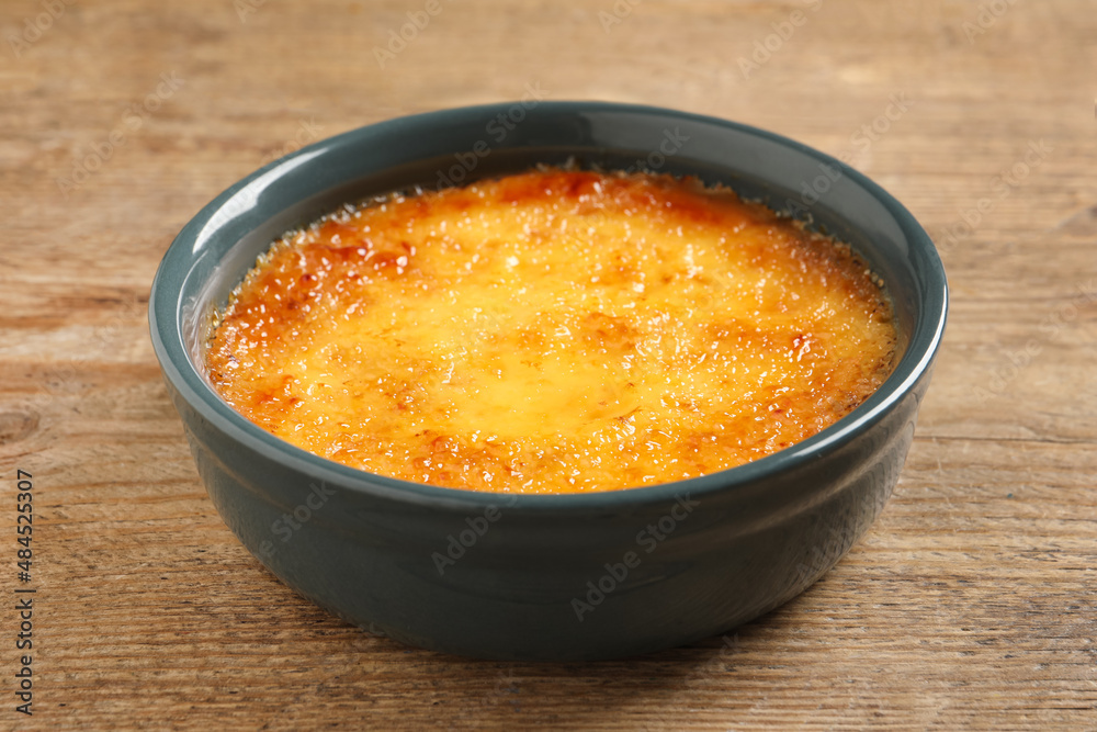 Delicious creme brulee in ceramic ramekin on wooden table, closeup Delicious creme brulee in ceramic ramekin on wooden table, closeup