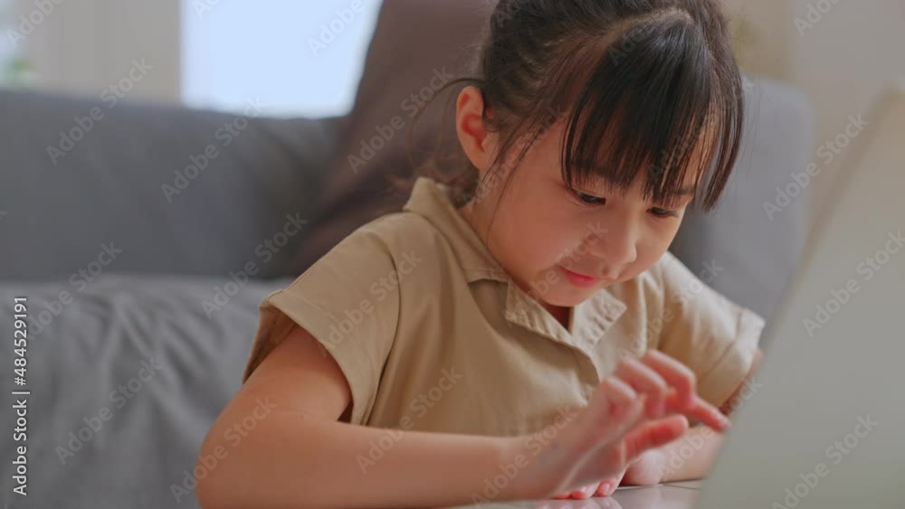 Curious cute preschool kid girl watching internet video course at home desk. back to School, Online learning, distance lesson, education at home, doing homework at home. Children tech addiction. Curious cute preschool kid girl watching internet video course at home desk. back to School, Online learning, distance lesson, education at home, doing homework at home. Children tech addiction.