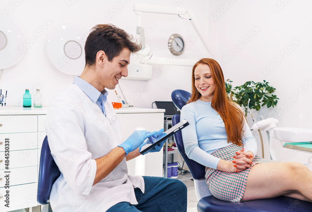 Obraz premium Cheerful dentist browsing treatment options near patient
