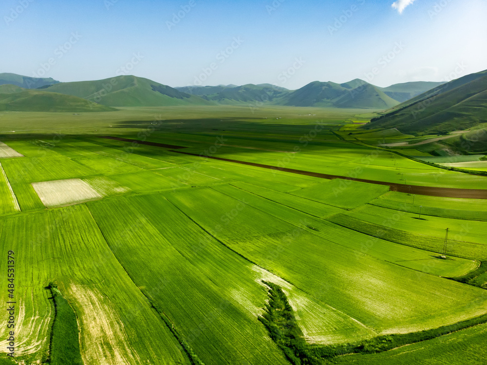 Aerial view of Piano Grande, large karstic plateau of Monti Sibillini mountains. Beautiful fields of the Monti Sibillini National Park, Umbria, Italy.