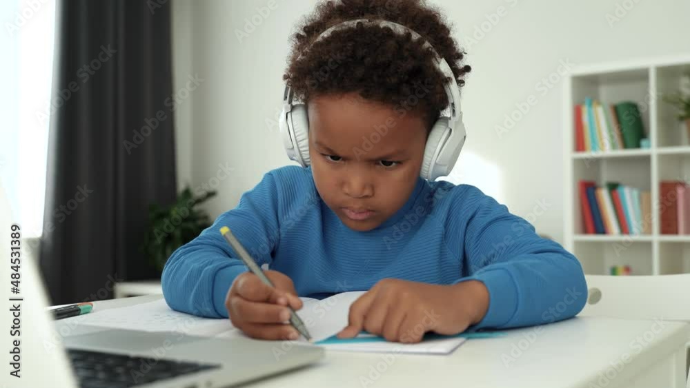 Smart primary school afro child boy learning writing, doing math homework sit at home table, adorable pretty little preschool kid studying alone making notes in pad. 4k footage Smart primary school afro child boy learning writing, doing math homework sit at home table, adorable pretty little preschool kid studying alone making notes in pad. 4k footage