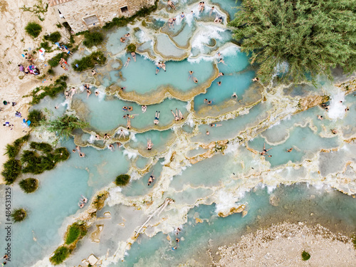 Aerial view of Terme di Saturnia, geothermal sulfur springs and natural spa with waterfalls at Saturnia thermal baths. People batching at Cascate del Mulino, Tuscany, Italy. photo