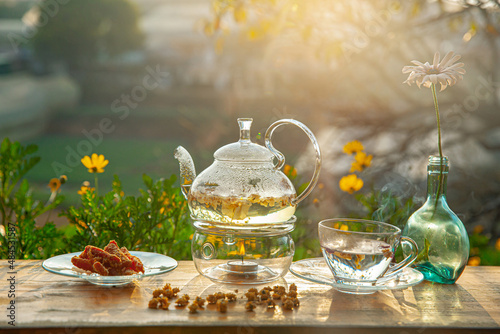 Chrysanthemum tea with hot steam and sweet potato jam on wooden table, in the backyard background in the afternoon sunlight
