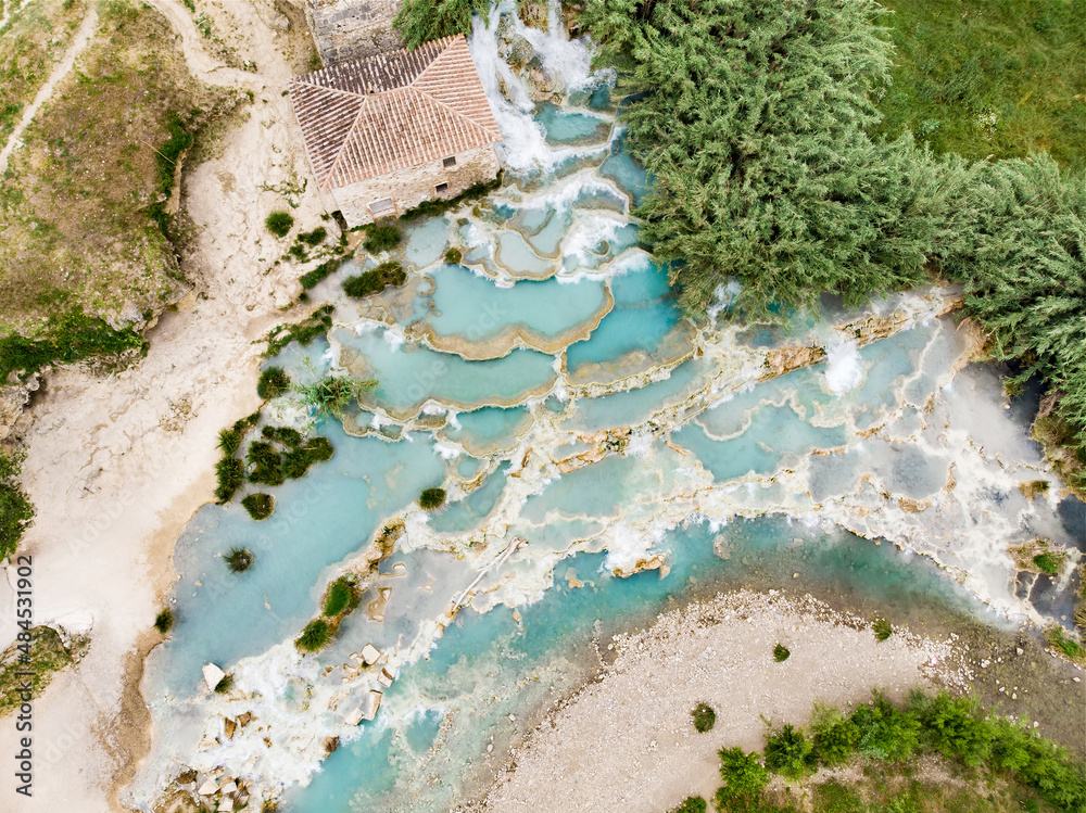 Aerial view of Terme di Saturnia, geothermal sulfur springs and natural spa with waterfalls at Saturnia thermal baths. People batching at Cascate del Mulino, Tuscany, Italy. - obrazy, fototapety, plakaty 