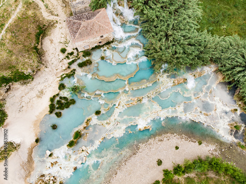 Aerial view of Terme di Saturnia, geothermal sulfur springs and natural spa with waterfalls at Saturnia thermal baths. People batching at Cascate del Mulino, Tuscany, Italy. photo