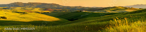 Stunning morning view of fields and farmlands with small villages on the horizon. Summer rural landscape of rolling hills, curved roads and cypresses of Tuscany, Italy.